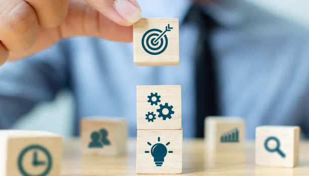 Concept of business strategy and action plan. Businessman hand putting wood cube block on top with icon