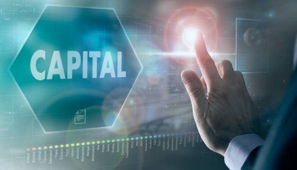 A businessman controlling a futuristic display with a Capital business concept on it.